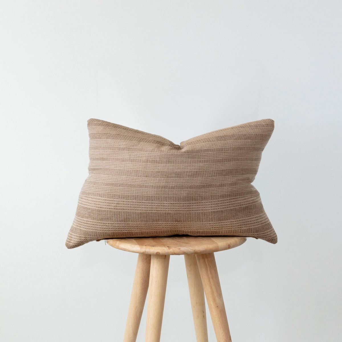 LUTHER lumbar cushion, brown woven stripe, on a wooden stool