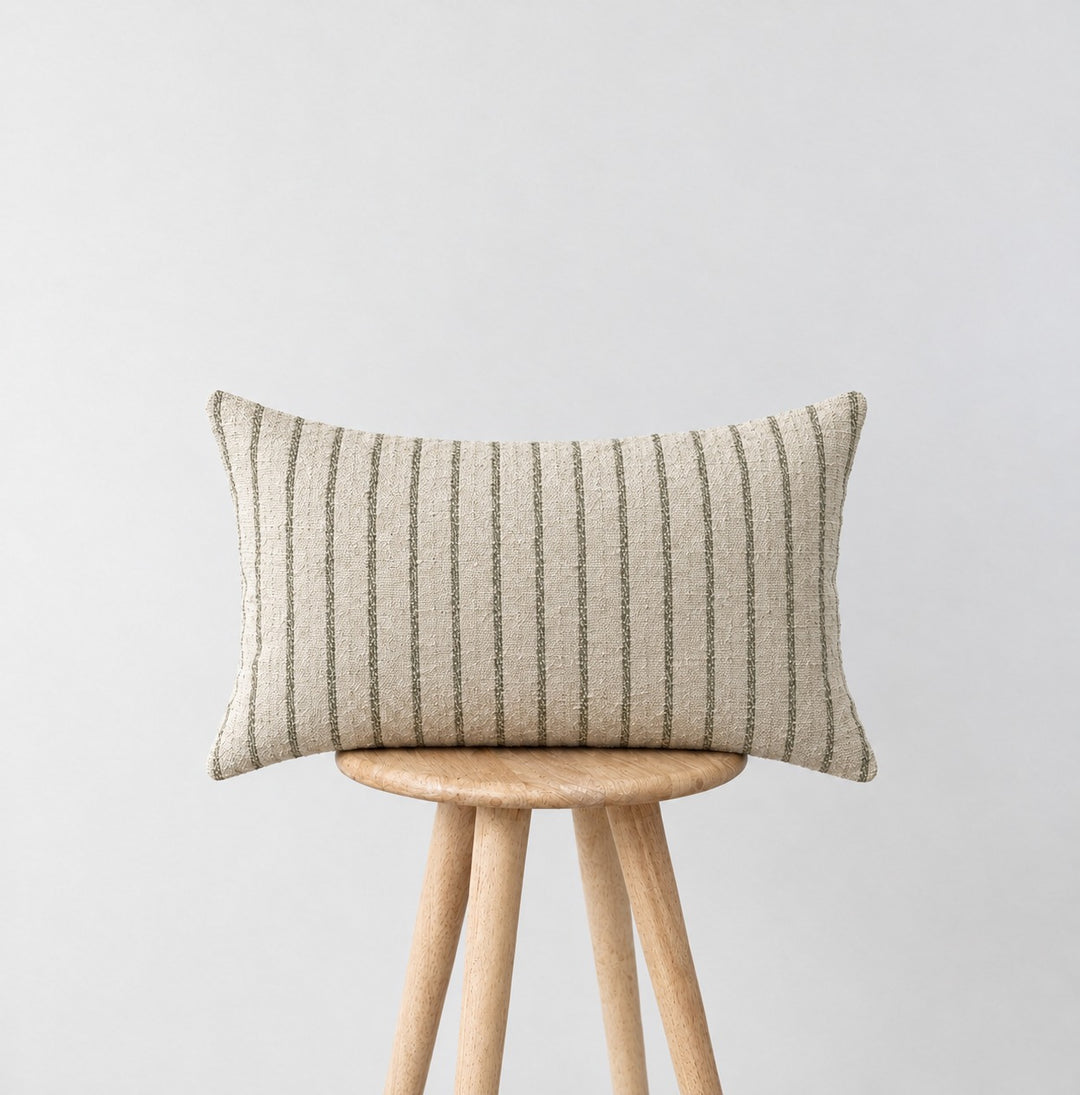 MARTY green striped lumbar cushion on a wooden stool