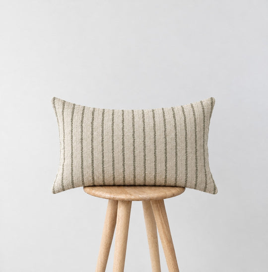 MARTY green striped lumbar cushion on a wooden stool